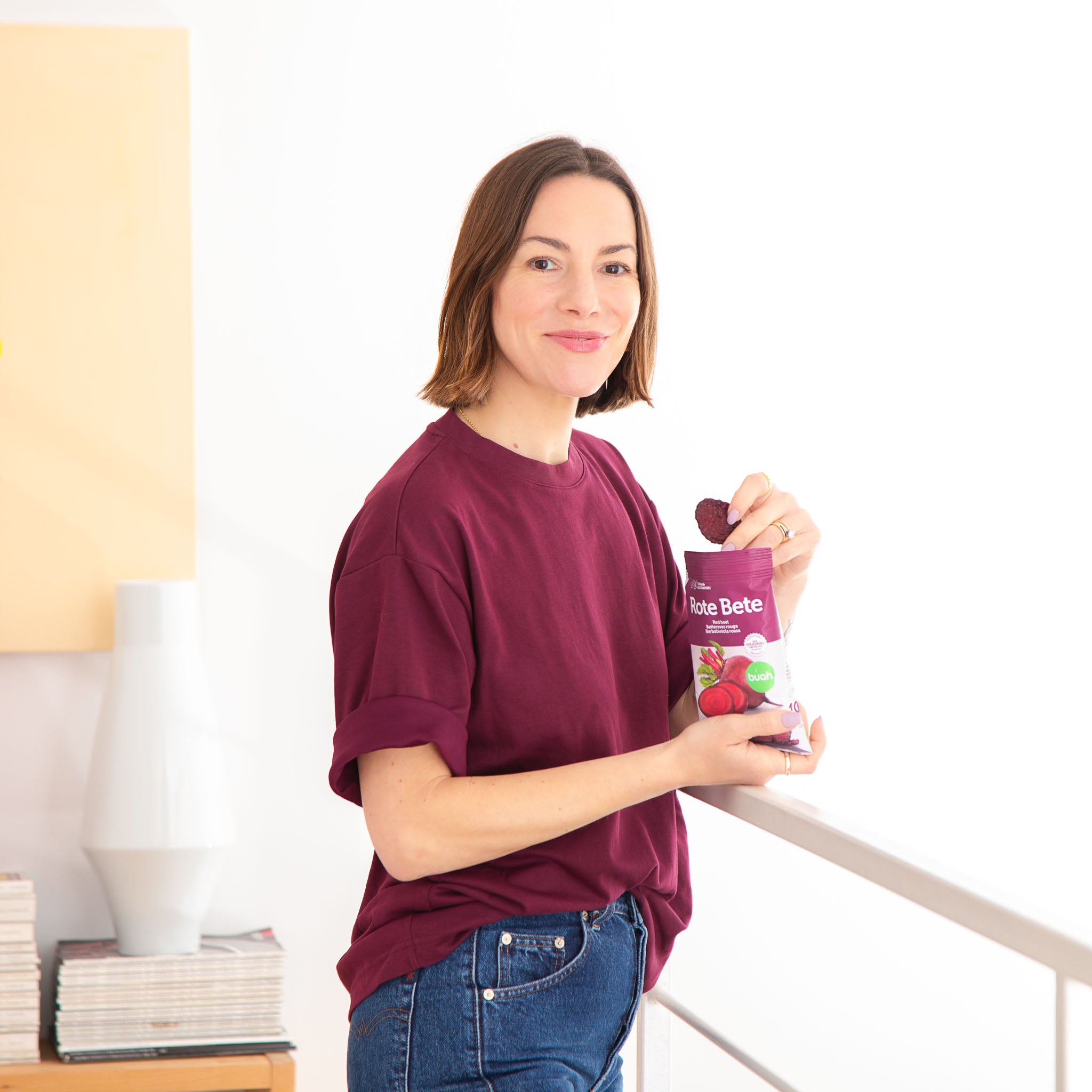 Frau in lila Shirt lacht in Kamera und isst buah Rote Bete Chips