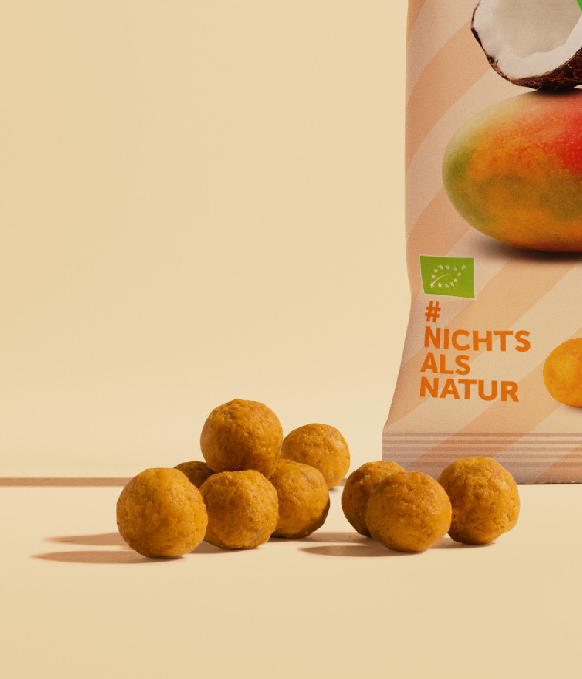 Kleine runde, orangene Mango-Kokos Kaubonbon von buah vor einer Verpackung Kaubonbons