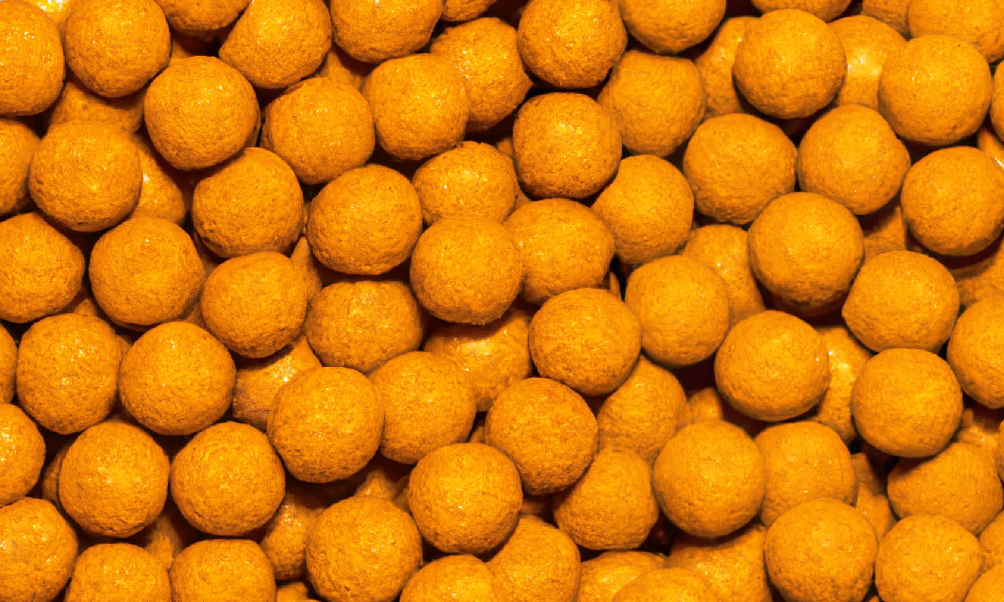 Viele kleine, runde und orangene Mango-Maracuja Kaubonbons von buah neben und aufeinander