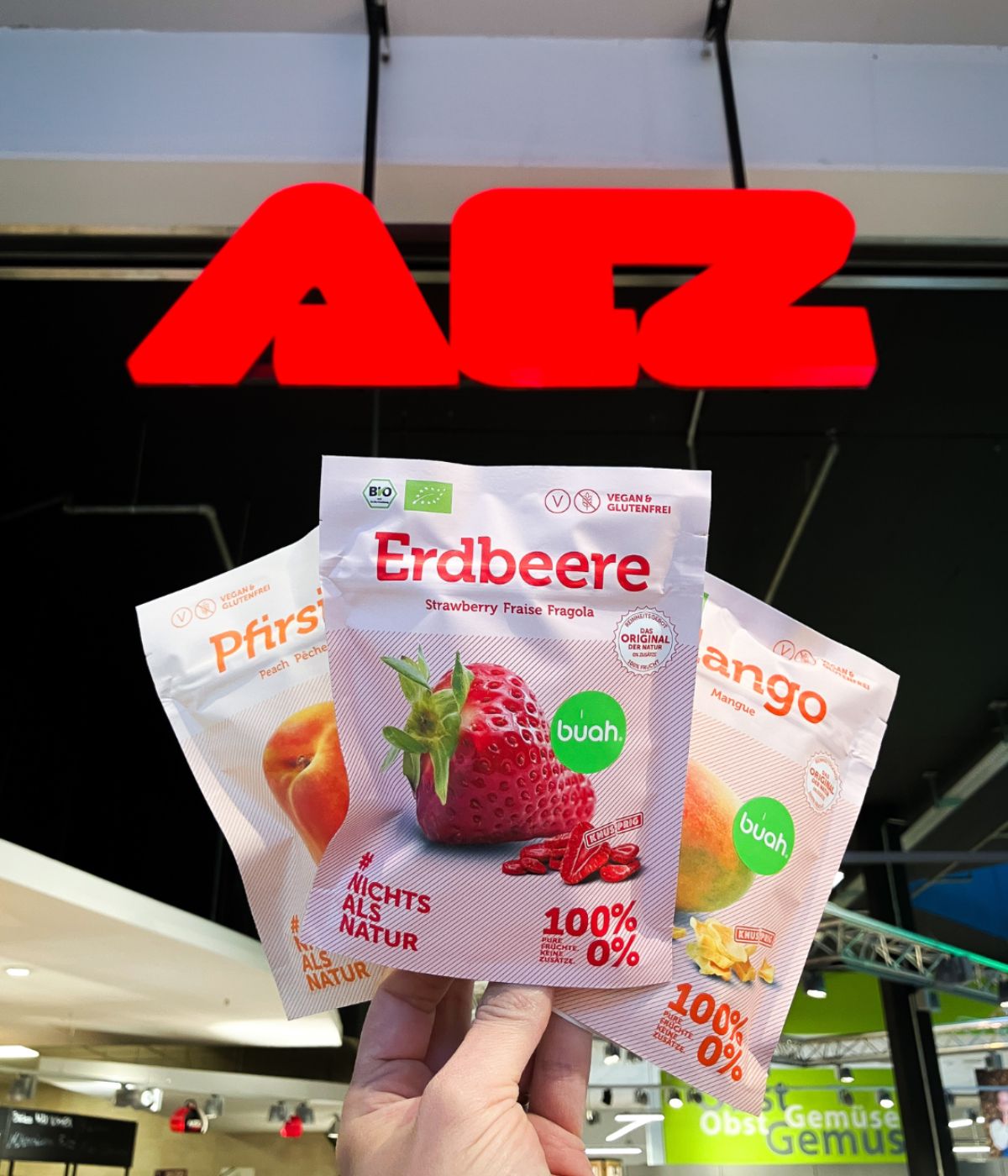 buah Instagram Posting, 3 Snackpacks, Pfirsich, Mango und Erdbeere  vor dem Schild des AEZ in München