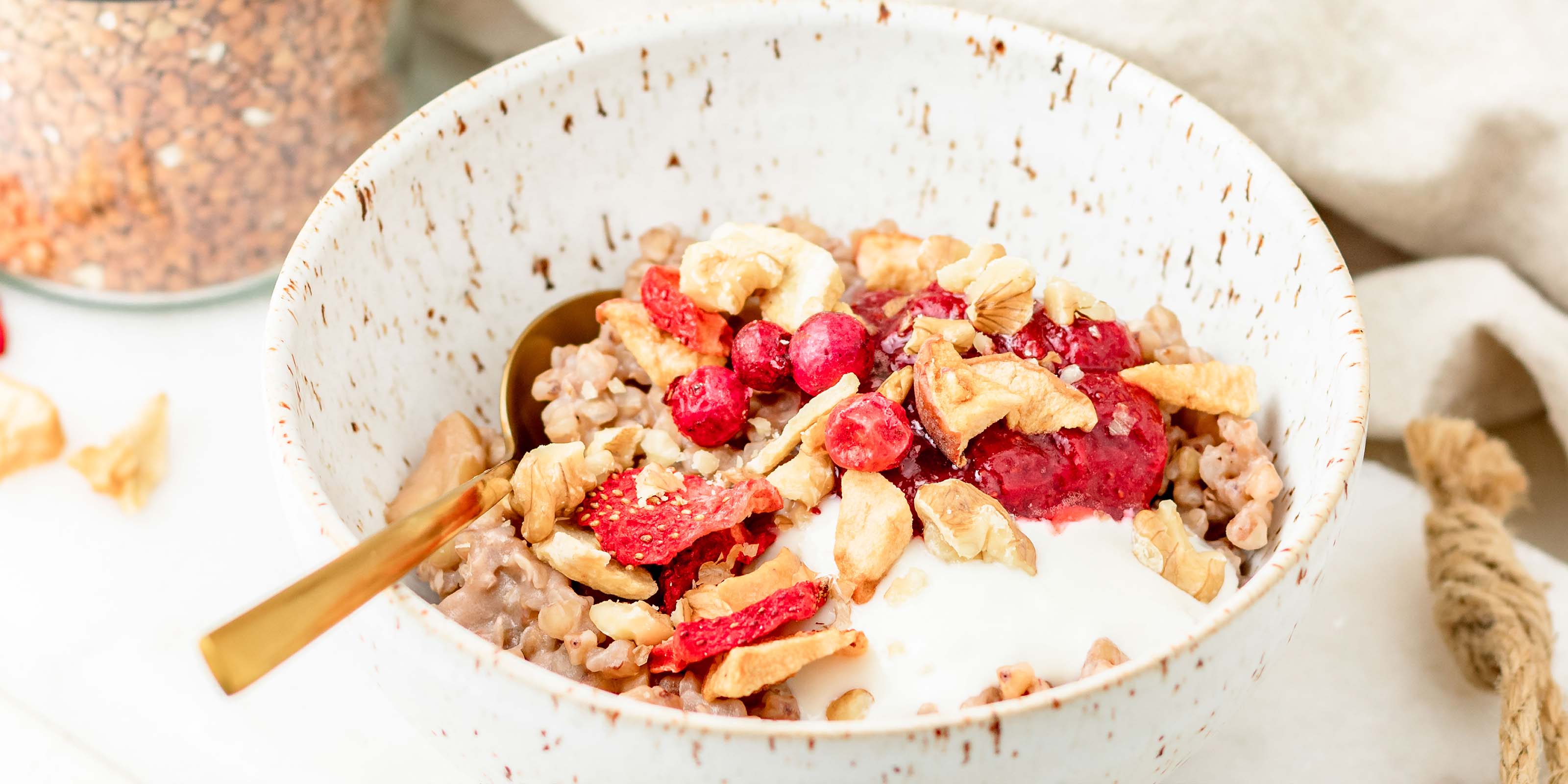 Buchweizen Porridge mit buah Erdbeeren und Apfel garniert in einer weißen Schale 